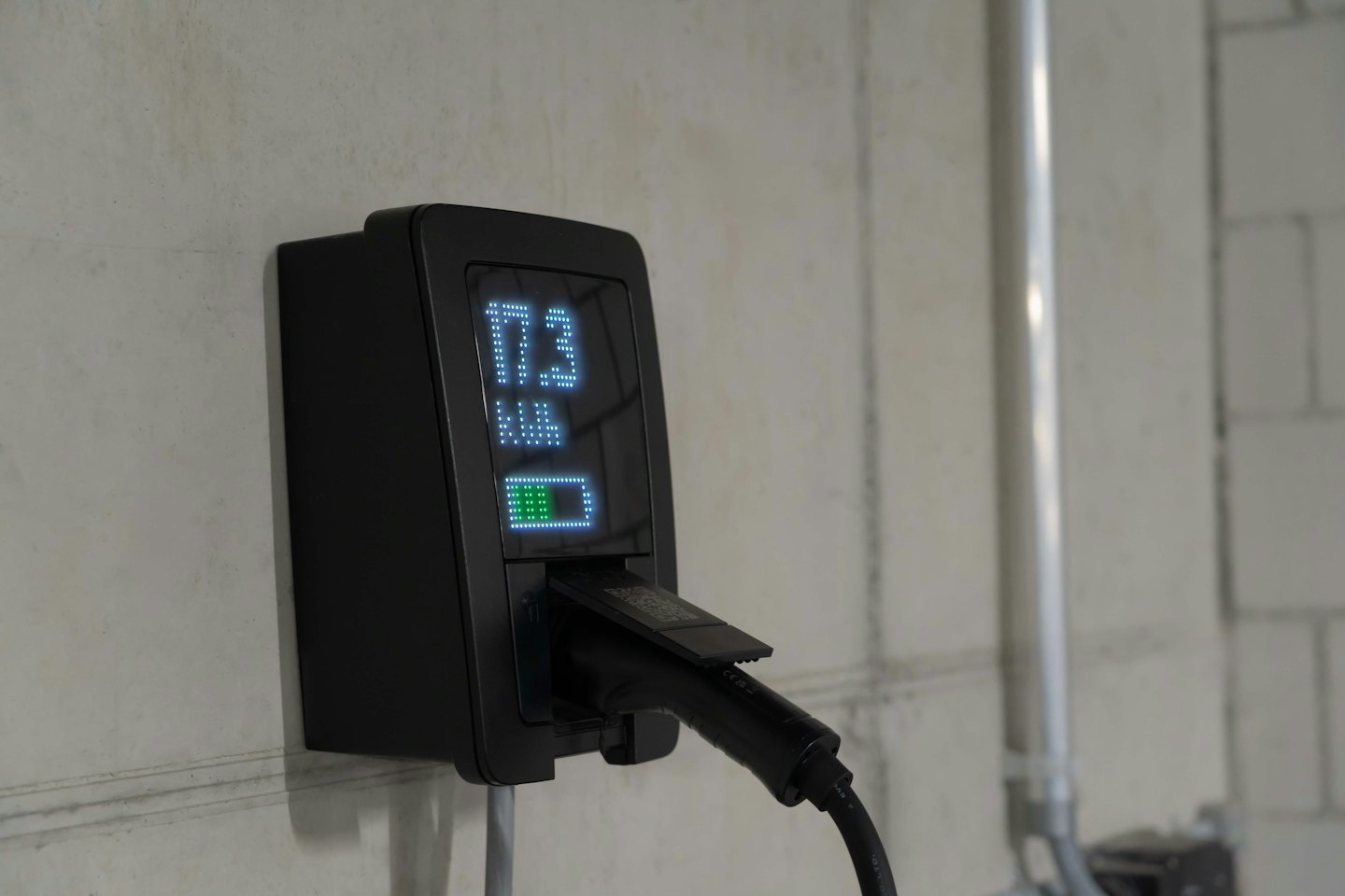 Cargador de vehículo eléctrico muestra el uso de energía en una pared de concreto.
